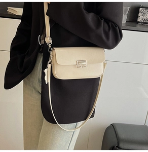 Close-up of cream rectangular leather crossbody bag with silver hardware and model styling