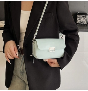 Detail of mint green leather crossbody bag with silver square metal lock and slim strap