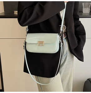 Detail of mint green crossbody bag with gold buckle worn on a black blazer outfit