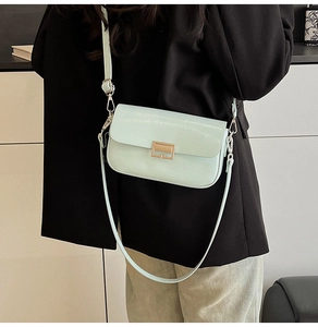 Light green leather crossbody bag with gold buckle shown on a professional model