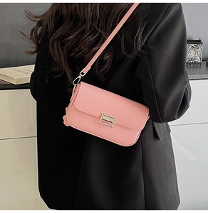 Detail of light pink crossbody bag with gold metal buckle and adjustable shoulder strap