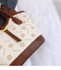 Detail of vintage tote bag with brown clover print and golden metal buckle on ivory leather