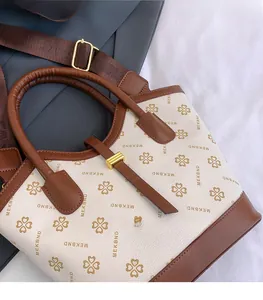 Detail of vintage monogram patterns and gold hardware on ivory leather handbag