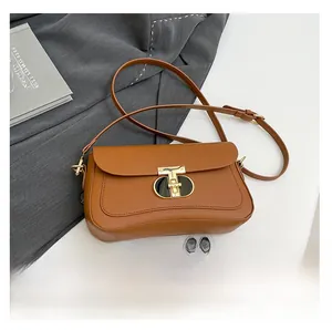 Détail d'un sac bandoulière en cuir marron avec boucle en T dorée et smartphone de référence
