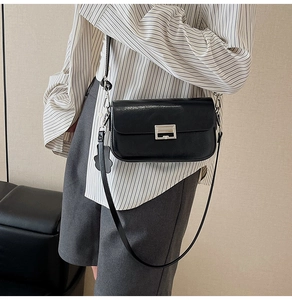 Detail of glossy black crossbody bag with silver metal buckle and cute bear pendant charm