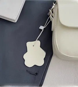Detail of off-white shoulder bag with textured leather and cute bear charm pendant