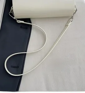 Detail of smooth cream leather shoulder strap with silver lobster clasp and hardware