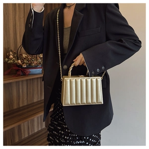 Detail of golden structured evening bag with vertical pleated texture and metallic handle