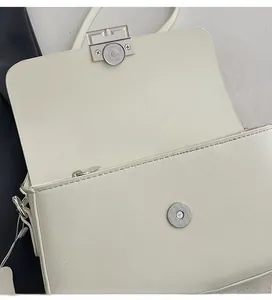 Close-up of premium silver magnetic buckle and leather texture on white crossbody bag