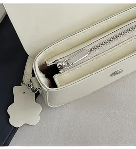 Detail view of smooth metal zipper and multi-compartment interior for shoulder bag