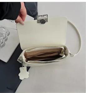Interior detail of ivory leather crossbody bag showing multi-layer compartments and zip pocket