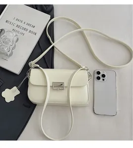 Macro shot of a cream leather crossbody bag showing size comparison with a smartphone