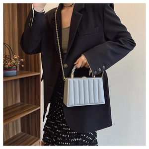 Detailed view of grey vertical textured box bag with gold chain and handle