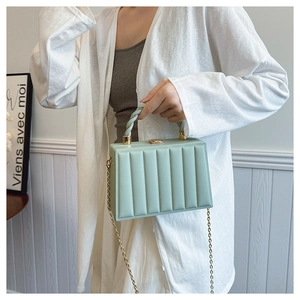 Close-up of mint green box bag with vertical pleats and golden chain strap