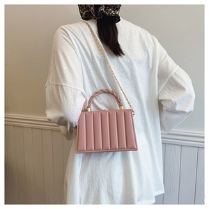 Detailed view of pink vertical quilted box bag with woven handle and gold chain strap