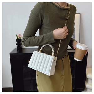Close-up of white vertical quilted box bag with pearl handle and gold chain strap