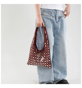 Detail of burgundy hobo bag with silver metallic studs worn with casual denim outfit