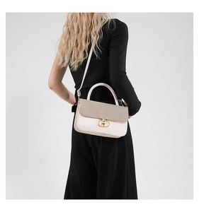 Detail of a chic cream patchwork handbag showing woven texture and gold metal buckle