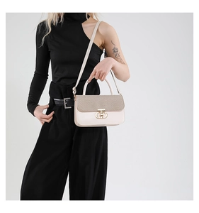 Detail of beige shoulder bag featuring woven textured flap and golden metal lock
