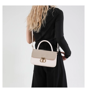 Detail of contrast crossbody bag with woven flap and gold twist lock on female model