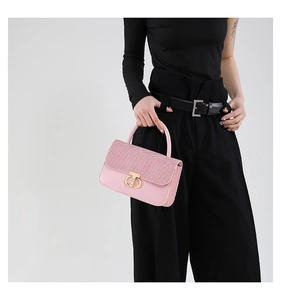 Detailed view of pink leather handbag featuring a woven flap and gold interlocking buckle