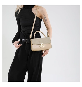 Detail of beige luxury handbag with woven texture, gold buckle and leather strap