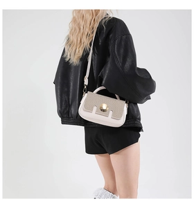 Detail of beige crossbody bag with golden round buckle and textured leather flap