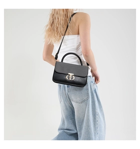 Detail of crossbody bag showing the gold interlocking metal lock and textured flap contrast