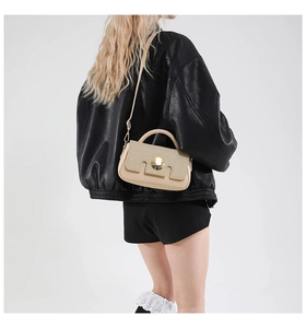 Detail of beige straw patchwork crossbody bag with gold buckle on a black leather jacket