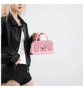 Détail du sac à main en cuir rose avec fermoir en métal doré et rabat texturé sur tenue noire