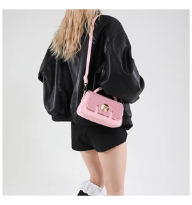 Sac bandoulière rose avec fermoir doré porté par un mannequin pour référence de style