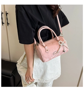 Close-up of pink snake skin embossed pillow bag with pearl bow and heart charm