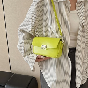 Neon green crossbody bag with silver buckle worn by a model in a striped shirt
