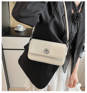 Chic cream leather crossbody bag with silver twist lock shown on a stylish model