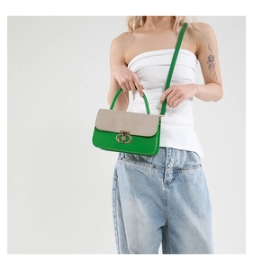 Detail of green leather handbag with beige woven texture flap and gold ring lock
