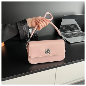 Detail of pink glossy leather handbag featuring a silver twist lock and knotted handle