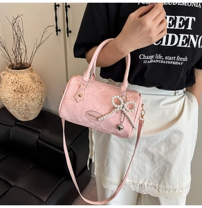 Detail of pink snake pattern Boston bag with pearl bow charm and metal logo plaque