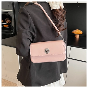 Detail of light pink rectangular shoulder bag featuring a silver circular turn-lock closure