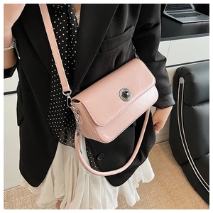 Close-up of light pink crossbody bag with silver twist lock on black blazer outfit