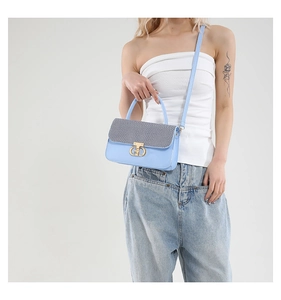Detail of light blue crossbody bag with gray textured flap and golden metal lock