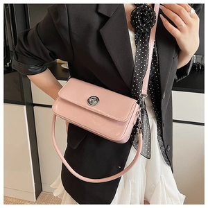 Detail of pink patent leather crossbody bag with silver clasp worn by model in suit