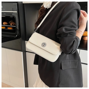 Detail of white glossy leather square bag with silver metal swivel lock on black blazer