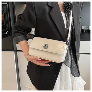 Close-up of off-white rectangular crossbody bag featuring a silver metal twist lock