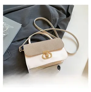Detail of the chic beige and khaki textured handbag with elegant gold clasp on grey suit fabric