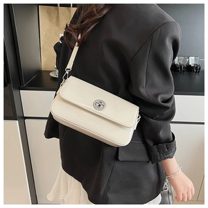 Creamy rectangular flap bag with silver twist lock shown on model shoulder