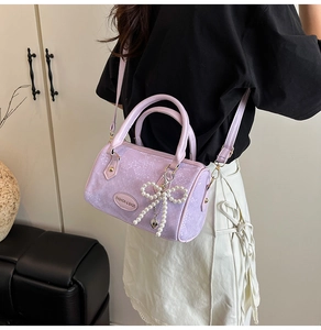 Detail of lavender snake-embossed mini Boston bag with pearl bow charm and logo plate