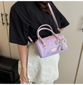 Detail of lavender python pattern barrel bag with pearl bow charm and golden hardware