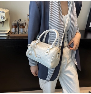 Detail of white Boston bag with snake-skin texture, pearl bow and heart charm