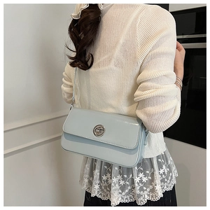 Close-up of light blue shoulder bag with glossy finish and silver circular buckle