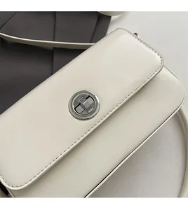 Detailed close-up of a white rectangular crossbody bag with a silver circular metal lock